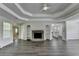 Open-concept living room features a stone fireplace, tray ceiling, and seamless flow to the kitchen at 3573 Plantation Pl, Loganville, GA 30052