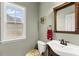 Bright bathroom features a pedestal sink, decorative mirror, and a window providing natural light at 7090 River Island Cir, Buford, GA 30518