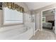 Bathroom featuring a large tub and glass enclosed shower with view of bedroom at 7090 River Island Cir, Buford, GA 30518