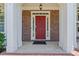 Eye-level closeup on a classic red front door, framed by white columns and brick facade at 7090 River Island Cir, Buford, GA 30518