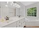 Modern bathroom with double sinks, sleek white cabinets, a large window, and a luxurious bathtub at 5055 Southland Dr, Woodstock, GA 30188
