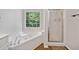 Well-lit bathroom featuring a jetted tub, a glass-enclosed shower, and wood flooring at 5055 Southland Dr, Woodstock, GA 30188