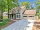Traditional two-story home with two-car garage and a concrete driveway surrounded by mature trees at 5055 Southland Dr, Woodstock, GA 30188