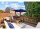 Wooden back deck with dining table, comfortable seating, an umbrella, and a backyard view at 5710 Waters Edge Trl, Roswell, GA 30075