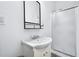 Bright bathroom featuring a shower with glass door, a modern sink, a wall mirror, and white walls at 5710 Waters Edge Trl, Roswell, GA 30075