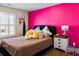 Bright bedroom featuring a pink accent wall, plush bedding, and a window with shutter blinds at 5105 Riverthur Pl, Duluth, GA 30096