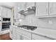 Close-up of a modern kitchen featuring quartz countertops, stainless steel gas cooktop, and white cabinetry at 1087 Halletts Peak Pl, Lawrenceville, GA 30044