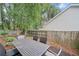 Outdoor dining set and chairs on a concrete patio, surrounded by a wood fence and lush trees at 172 Stoneforest Dr, Woodstock, GA 30189