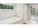 Bright bathroom with a soaking tub, white tile, and view to the backyard at 1054 Foreststone Sw Way, Marietta, GA 30064