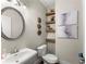 Stylish half-bathroom featuring modern fixtures, floating shelves with decorative items, and a round mirror at 109 Bellehaven Dr, Woodstock, GA 30188