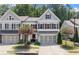 Charming townhome featuring gray siding, brick accents, a two-car garage, and a beautifully landscaped front yard at 109 Bellehaven Dr, Woodstock, GA 30188
