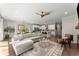 Sunlit living room featuring an area rug, ceiling fan, and seamless flow to the modern kitchen and dining area at 109 Bellehaven Dr, Woodstock, GA 30188
