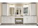 Bright bathroom featuring double sinks, white cabinetry, decorative mirrors, and elegant lighting fixtures at 7125 Heard Rd, Cumming, GA 30041