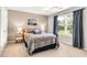 Comfortable bedroom featuring a large window with curtains, ceiling fan, and a bed with patterned bedding at 7125 Heard Rd, Cumming, GA 30041