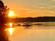 Golden sunset reflecting on a calm lake with boat docks and tranquil scenery at 7125 Heard Rd, Cumming, GA 30041