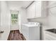 Bright laundry room with washer, dryer, cabinets, utility sink, and wood-look floors at 7125 Heard Rd, Cumming, GA 30041