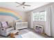 Bright Bedroom with a rainbow wall design, white crib, and cozy gray rocking chair at 5070 Hensley Dr, Atlanta, GA 30338