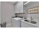 Well-organized laundry room with white cabinetry, modern washer and dryer, and a convenient utility sink at 579 Brashy St, Woodstock, GA 30188