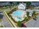 Aerial view of a community pool area with splash pad, umbrellas, lounge chairs, and landscaped surroundings at 579 Brashy St, Woodstock, GA 30188