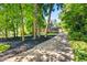 View of a brick two-story house with a long driveway, mature trees, and black mulch landscaping at 285 Jade Cove Dr, Roswell, GA 30075