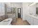 Bright bathroom with a soaking tub, a glass-enclosed shower, double sink vanity with white countertop, and gray doors at 4720 Down Setting Rd, Cumming, GA 30028