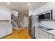Open kitchen area with white cabinets, stainless appliances, hardwood flooring, and access to the staircase at 1360 Mount Mickinley Dr, Grayson, GA 30017