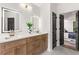 Bathroom featuring dual sinks, wood cabinets, quartz countertops, LED mirrors, and a doorway to the bedroom at 3208 Spruce Way, Atlanta, GA 30349