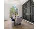 Elegant dining room featuring a modern light fixture, statement wall and large window overlooking the landscaped yard at 3208 Spruce Way, Atlanta, GA 30349