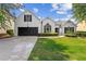 Charming white brick home featuring a lush green lawn, manicured shrubs and a black garage door at 3208 Spruce Way, Atlanta, GA 30349