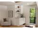 Bright beverage center featuring a sink, cabinets, floating shelves and an adjacent seating area at 1155 Peachtree Battle Nw Ave, Atlanta, GA 30327