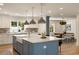 A kitchen with white cabinets, a blue island, stainless steel pendant lights, and a stone backsplash at 1155 Peachtree Battle Nw Ave, Atlanta, GA 30327