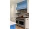 Close up of a stainless steel Wolf range with a blue vent hood and white cabinets at 1155 Peachtree Battle Nw Ave, Atlanta, GA 30327
