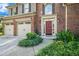 A beautiful brick home featuring a red door, green shrubs, and a two-car garage at 3117 Blowing Wind Nw Ct, Acworth, GA 30101