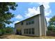 Two-story home exterior with a tall chimney, backyard patio, and wooded surroundings at 574 Friars Head Dr, Suwanee, GA 30024