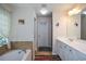 Bright bathroom featuring dual sinks, granite counter tops and a soaking tub with tile surround at 574 Friars Head Dr, Suwanee, GA 30024