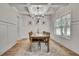 Bright dining room boasts white wainscoting, grid ceiling, stylish chandelier, and warm wood flooring at 1611 Alcovy Station Rd, Covington, GA 30014