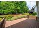 A spacious brown deck with railings overlooks a lush, green yard filled with mature trees and plants at 454 Pine Bluff Dr, Dallas, GA 30157