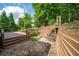 A stone patio and tiered deck lead to a lush green yard with mature trees and a small rock waterfall feature at 454 Pine Bluff Dr, Dallas, GA 30157