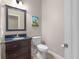 Bathroom features a dark vanity, toilet, mirror with wall sconces and a door for entry at 570 Mcgarity Dr, Mcdonough, GA 30252