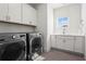 Bright laundry room featuring modern washer and dryer, cabinets, sink, and wood-look tile flooring at 779 Keystone Dr, Woodstock, GA 30188