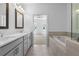 Bathroom featuring a soaking tub, a glass-enclosed shower, and double vanities with light grey cabinetry at 5440 Howington Ct # 190, Buford, GA 30518