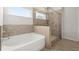 Well-lit bathroom with a separate tub and walk-in shower with gray stone tiling at 7410 Ansley View Ln, Cumming, GA 30028