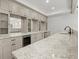 Kitchen featuring gray cabinets, wine cooler, granite countertops, and glass door cabinets at 7410 Ansley View Ln, Cumming, GA 30028