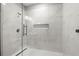 Walk-in shower with marble tile, built-in shelving, and frameless glass door at 7410 Ansley View Ln, Cumming, GA 30028