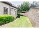 A well-maintained backyard featuring a brick retaining wall, mature landscaping, and lush green lawn at 9695 Almaviva Dr, Alpharetta, GA 30022