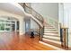 Elegant foyer with a curved staircase featuring iron railings and hardwood floors, leading to an open living space at 9695 Almaviva Dr, Alpharetta, GA 30022