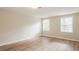 Comfortable bedroom featuring wood-look floors and natural light from two large windows at 110 Paddock Trl, Peachtree City, GA 30269