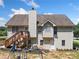 Exterior rear view of the home with a deck, chimney, and a spacious yard with playset at 2355 Woodland Hills Dr, Cumming, GA 30040