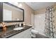 Bathroom features a granite countertop, white cabinets, shower-tub combo and decorative shower curtain at 2355 Woodland Hills Dr, Cumming, GA 30040