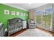 Bedroom featuring a green accent wall, hardwood floors, and large windows for lots of light at 2355 Woodland Hills Dr, Cumming, GA 30040
